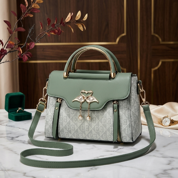 Green and gray handbag with decorative elements on a marble surface with jewelry in the background.