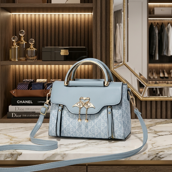 Light blue handbag with gold accents on a marble surface, with a background of books and a mirror.