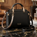 Black handbag with gold accents on a marble surface, brand 'FOXER' visible