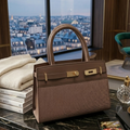 Brown handbag on a marble surface with a cityscape view through a window.