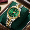 Luxury watch with green face and gold accents on a green cushion