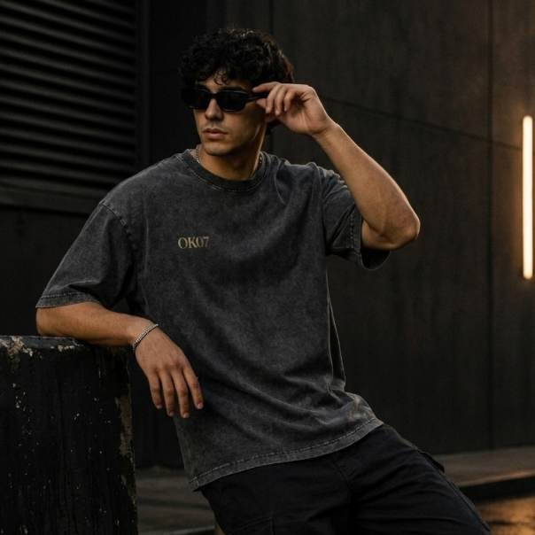 Man wearing a dark t-shirt with 'OKC' text, sitting against a dark background.