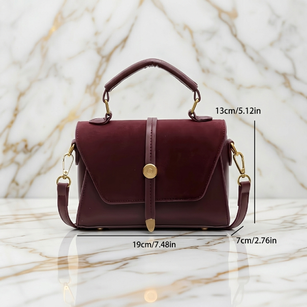 Maroon handbag with gold accents on a marble background