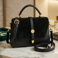 Black handbag with gold accents on a marble surface