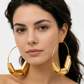 Woman wearing gold hoop earrings against a neutral background