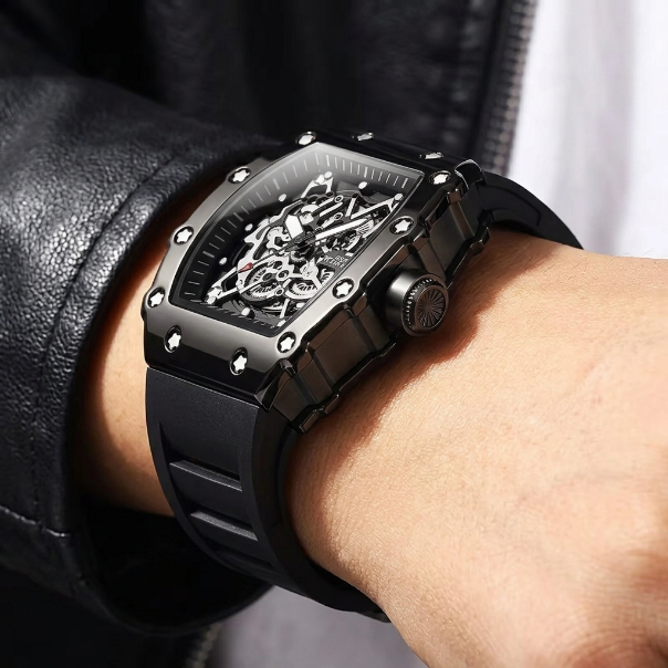 Black skeleton watch on a person's wrist with a blurred background