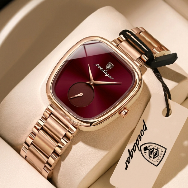 Rose gold watch with red face and matching tag on beige surface