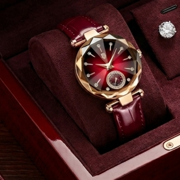 Luxury watch with red face and maroon leather strap in a jewelry box